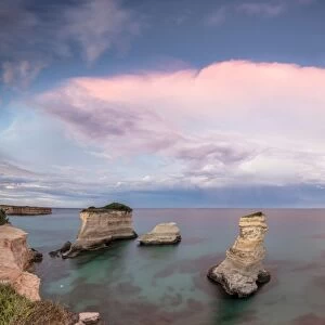 Pink sunset frames the cliffs known as Faraglioni di Sant Andrea and the turquoise sea