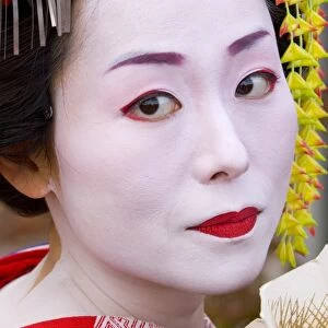 Portrait of a geisha holding a traditional paper fan