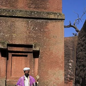 Priest holding cross swings an incense burner at the rock-hewn monolithic church of Bet Giyorgis