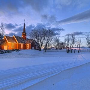 The red church of Flakstad surrounded by snow at dusk, Lofoten Islands, Arctic, Norway