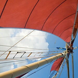 Red sails on sailboat that takes tourists out for sunset cruise