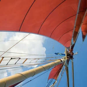 Red sails on sailboat that takes tourists out for sunset cruise