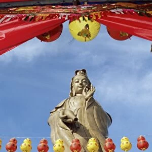 Red and yellow lanterns in front of the standing statue of Kuan Yim