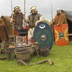 Roman soldiers of the Ermine Street Guard in encampment relaxing around the campfire