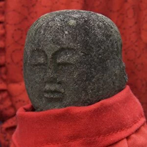 Small stone figure wearing traditional red dress