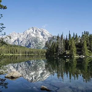 Snow-capped mountains reflected in the calm waters of Leigh Lake, Grand Teton National