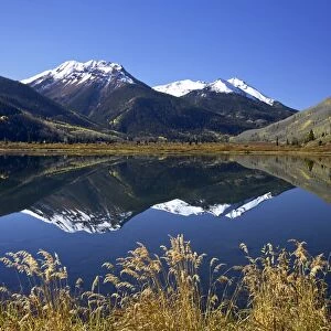 Snow-capped Red Mountain reflected in Crystal Lake with fall colors
