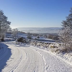 Snowy, bendy country lane with stone walls and trees, Curbar Edge, Peak District National Park, Derbyshire, England, United Kingdom, Europe