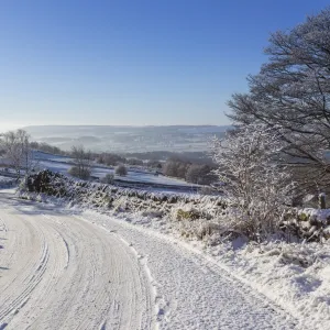 Snowy, bendy country lane with stone walls and trees, Curbar Edge, Peak District National Park, Derbyshire, England, United Kingdom, Europe