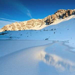 Snowy peaks reflected in the icy Lake, Piz Umbrail at dawn, Braulio Valley, Valtellina
