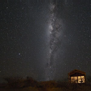 South hemisphere Milky Way and a small illuminated hut, Namibia, Africa