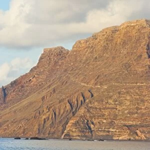 Spectacular 600m volcanic cliffs of the Risco de Famara rising over Lanzarotes finest surf beach at Famara in the north west of the island, Famara, Lanzarote, Canary Islands, Spain, Atlantic