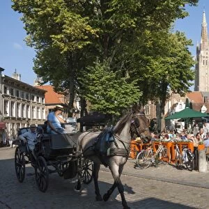 Square with cafe, horse and carriage, and spire of Church of Our Lady, Bruges, Belgium