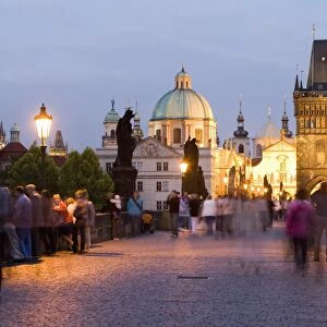 Statues and crowds on the Charles Bridge, with the dome of the Church of St