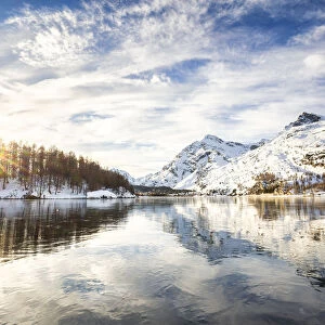 The sun illuminates the icy surfaces of Lake Sils, Engadine Valley, Graubunden