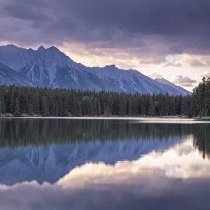 Sunrise over the mountains of the Rockies, reflected in Johnson Lake, Banff National Park