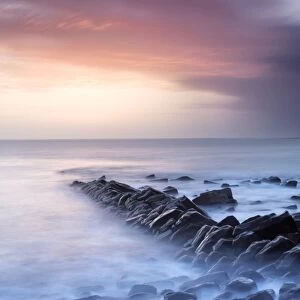 Sunset on a stormy winters day looking across Kimmeridge Bay from the remains of Clavells Pier, Kimmeridge, near Swanage, Dorset, England, United