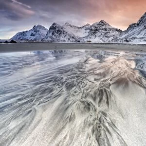 Sunset on the surreal Skagsanden beach surrounded by snow covered mountains, Flakstad