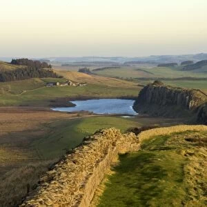 Towards sunset, view east along Hadrians Wall from Windshields Crag to Crag Lough and Hotbank Farm, UNESCO World Heritage Site, Northumberland National Park, Northumbria, England, United Kingdom, Europe