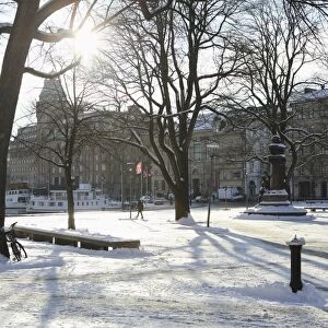 Sunshine in the snow-covered Berzelii Park, by the waterfront at Nybroviken, in Stockholm
