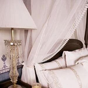 Detail of side table and four poster bed in bedroom