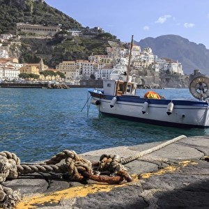 Tethered fishing boat with rope, Amalfi harbour, from quayside with view towards Amalfi town