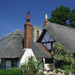 Thatched cottages, with the village church behind, at Welford on Avon in Warwickshire