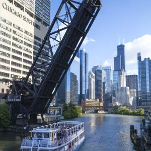 Tour boat passing under a raised disused railway bridge on the Chicago River, Downtown towers in the background, Chicago, Illinois, United States of America, North America