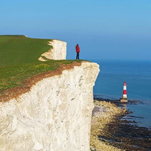 Tourist stands on top of the cliff overlooking Beachy Head lighthouse, Seven Sisters chalk cliffs, South Downs National Park, East Sussex, England, United Kingdom, Europe