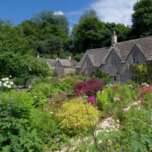 Traditional Cotswold stone cottages with colourful flower gardens, Bibury