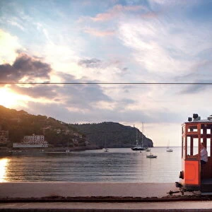 Tram at sunset set against yachts in bay, Soller, Mallorca, Balearic Islands