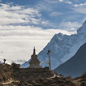 Trekkers near a chorten in the Everest region with the peak of Ama Dablam in the distance