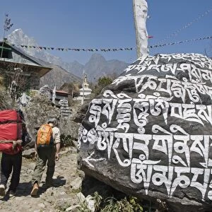 Trekkers walking past a mani stone, Solu Khumbu Everest Region, Sagarmatha National Park