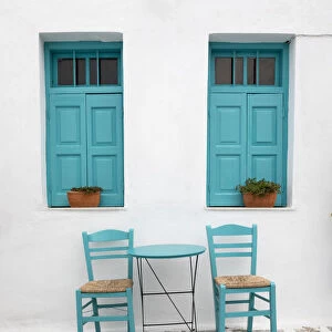 Typical Greek cafe table and chairs with shuttered windows, Pano Chora, Serifos, Cyclades