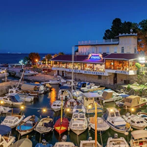 View of cafe and restaurant overlooking boats in harbour at dusk, Lovran village, Lovran, Kvarner Bay, Eastern Istria, Croatia, Europe
