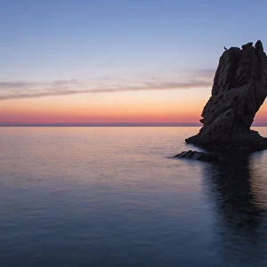 View from Calura Bay across the Tyrrhenian Sea, dawn, rock stack silhouetted against