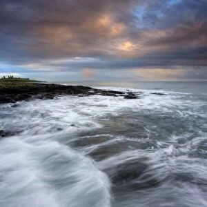 View along coastline on a stormy day towards the ruins of Dunstanburgh Castle