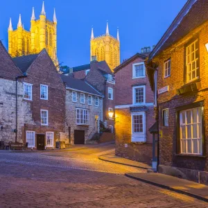 View of illuminated Lincoln Cathedral viewed from the cobbled Steep Hill at dusk