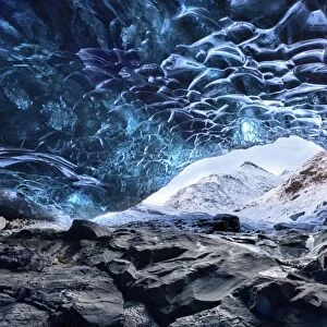 View from inside ice cave under the Vatnajokull Glacier towards snow covered mountains