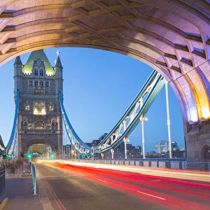 View of North Tower of Tower Bridge and car trail lights at dusk, London, England