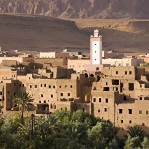 View over the town of Tinerhir showing crumbling kasbahs, palm groves and a modern minaret