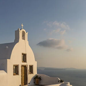 View of traditional white washed Church at sunset in Oia, Santorini, Greek Islands