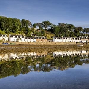 Village of Plockton bathed in early morning light and reflecting in calm sea at low tide