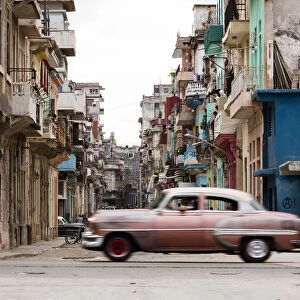 A vintage American car driving across a street in Havana, Cuba, West Indies, Caribbean