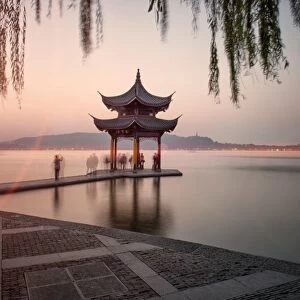 Visitors are taking the last shots with a pagoda at West Lake as the sun is sinking, Hangzhou, Zhejiang, China, Asia