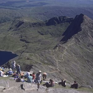 Walkers relaxing at the summit of Mount Snowdon, with Llyn Llydaw reservoir