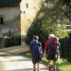 Two walkers with rucksacks on the Cotswold Way footpath, Stanton village