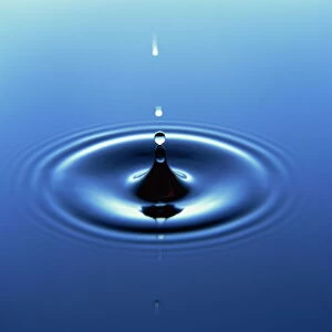 Water droplet hitting water surface creating ripples