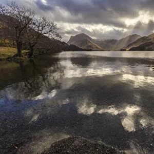 Winter reflections, shafts of sunlight break through clouds, Buttermere, Lake District