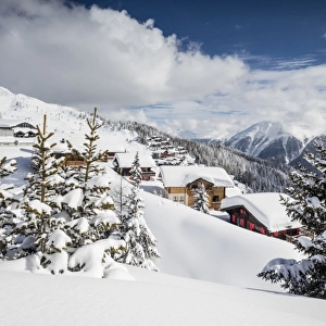 The winter sun shines on the snowy mountain huts and woods, Bettmeralp, district of Raron